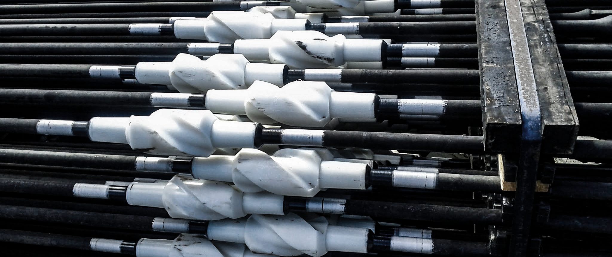 Coupled sucker rods with white rod guides, on a rack