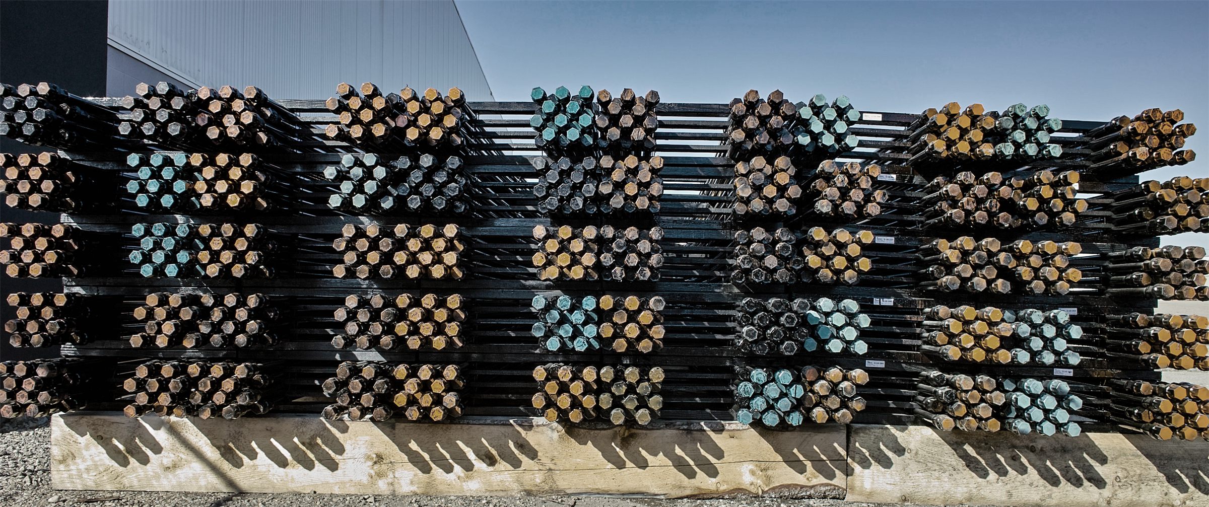 Stacks of sucker rods with coloured ends, on racks